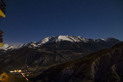 Scenic view of snowcapped mountains against sky at night