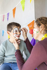 Mother painting her son's face like a clown