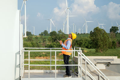 Man standing by railing against sky