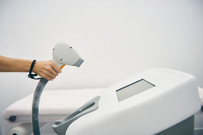 Close-up of hand holding smart phone over white background