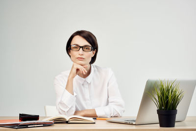 Portrait of businesswoman sitting against white background