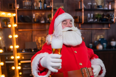 Portrait of santa clause holding beer at home