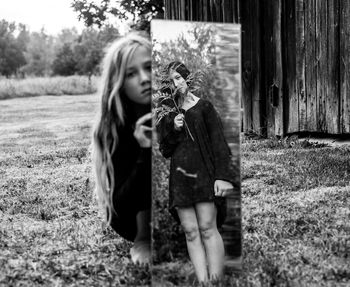 Portrait of girl holding mirror with reflection of female on grass