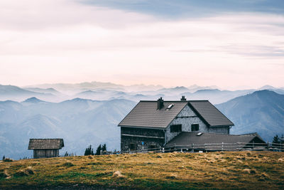 Houses on mountain against cloudy sky