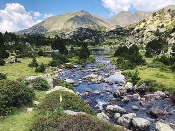 Scenic view of stream by rocks against sky