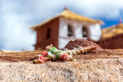 Close-up of a small wooden cross with machuca church in the background