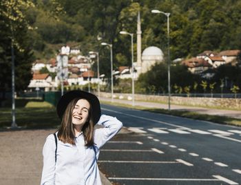 Smiling young woman wearing hat standing on road