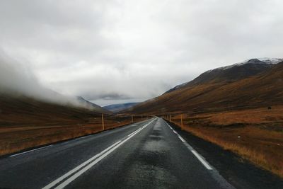 Road leading towards mountains against sky