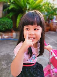 Cute girl with hand raised looking away while sitting outdoors