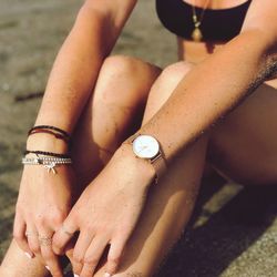 Midsection of woman sitting at sandy beach