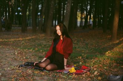 Young woman sitting on tree trunk in forest