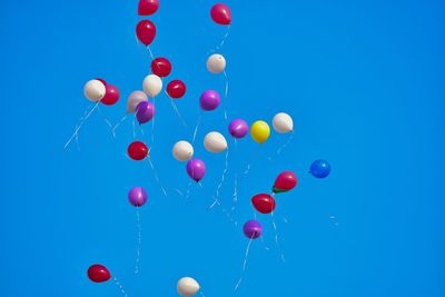 Low angle view of balloons against blue sky