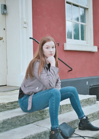 Beautiful young woman sitting outside house