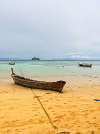 Boat moored on beach against sky