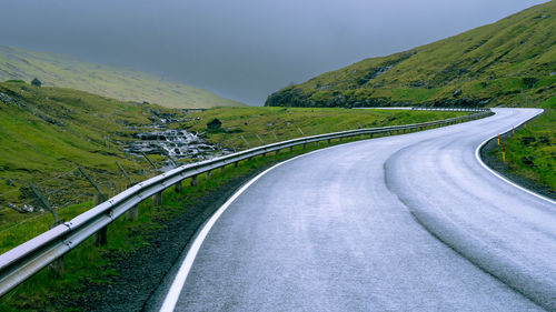 Empty road amidst mountains against sky