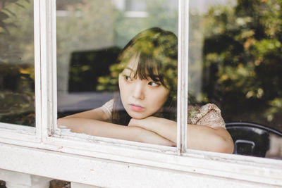 Portrait of young woman at window