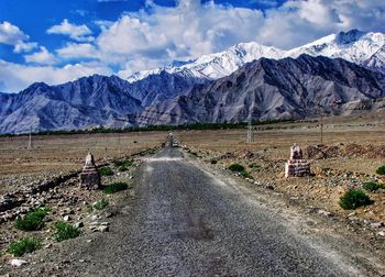 Road by snowcapped mountains against sky