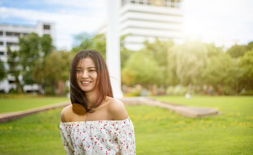 Portrait of smiling young woman standing against at park