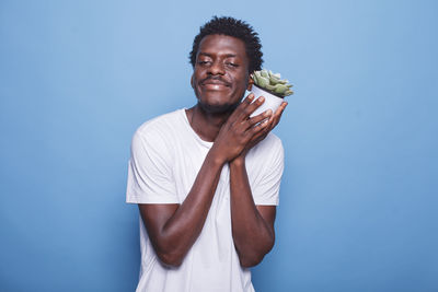 Portrait of young woman holding gift against blue background