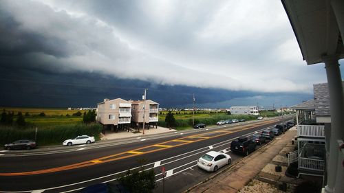 High angle view of cars parked on road against cloudy sky