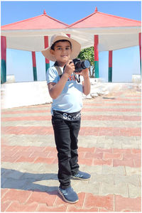 Full length of young boy holding camera 