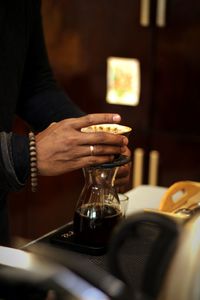 Midsection of man preparing coffee on table