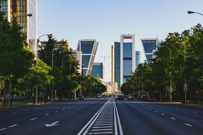 Road by buildings in city against sky