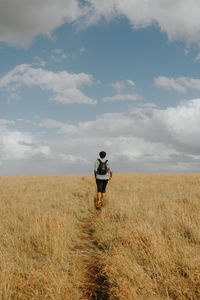 Rear view of man standing on field against sky