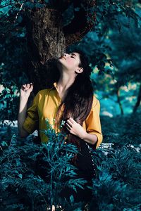 Woman looking away against trees