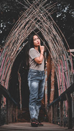 Portrait of young woman standing against trees at night