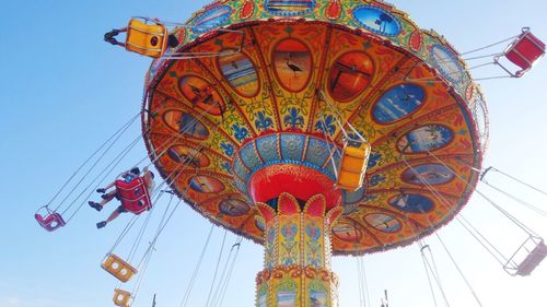 Low angle view of colorful chain swing ride spinning against sky