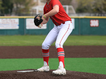High school baseball pitcher on the mound throwing a pitch during a game.