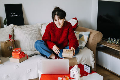 Portrait of woman using digital tablet while sitting on sofa at home