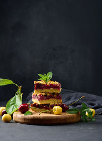 Square slices of cherry crumble lie in a stack on a black background