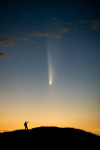 Silhouette man walking on field against sky at night