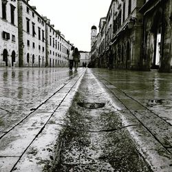Wet sidewalk in city against sky