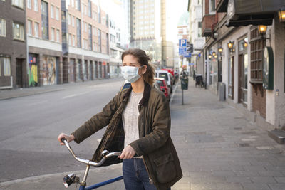 Woman with bicycle wearing face mask