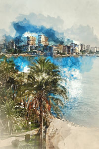 Scenic view of sea by cityscape against sky