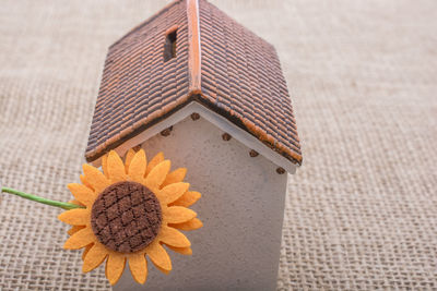 Close-up of artificial sunflower with model home on table