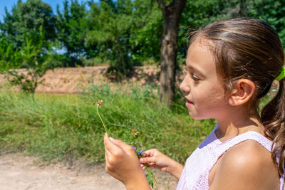 Cute girl holding plant outdoors