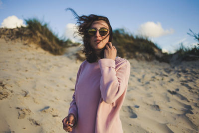 Young woman wearing sunglasses standing on beach