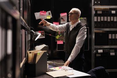 Side view of woman using mobile phone while standing in office