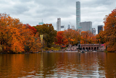 Scenic view of river by buildings against sky during autumn
