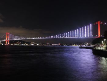 Illuminated bridge over river at night