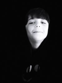 Portrait of smiling boy against black background