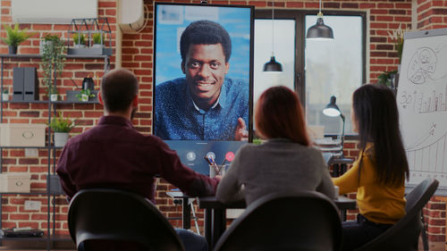 Rear view of business people talking on video conference at office