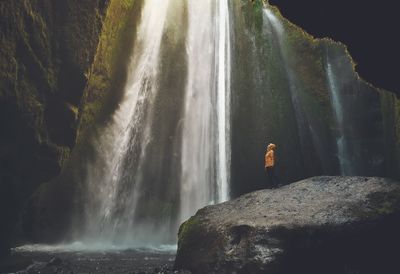 Full length of man standing on rock against waterfall
