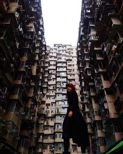 Side view of woman standing amidst buildings in city