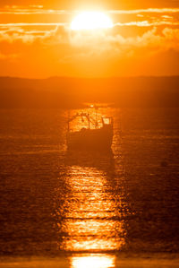 Scenic view of fishing boat in sea against sky during sunset