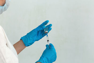 Cropped hands of doctor holding syringe with vial at hospital